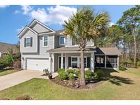 Charming two-story home boasts a well-maintained lawn, inviting front porch, and attached two car garage at 4021 Brown Trout Dr, Johns Island, SC 29455
