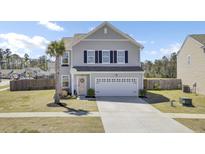 Charming two-story home with a well-maintained lawn, a palm tree, and an attached two-car garage at 101 Corvus Ct, Summerville, SC 29486
