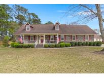 Charming brick home featuring dormer windows, manicured landscaping, and a welcoming front porch at 117 Hartin Blvd, Summerville, SC 29486