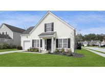 Charming, light yellow, two-story home with black shutters and a well-manicured lawn at 1249 Shadow Mist Ln, Charleston, SC 29492