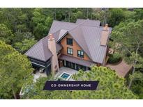 A captivating aerial view of a house with a metal roof, surrounded by lush greenery and a private pool at 127 Blue Heron Pond Rd # A, Kiawah Island, SC 29455