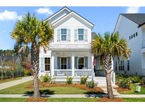 Charming two-story white home with a welcoming front porch and lush landscaping with palm trees in a quiet neighborhood at 1772 Agate Bay Dr, Mount Pleasant, SC 29466