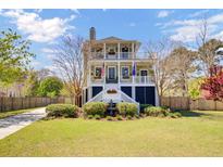 Charming two-story home with a double front porch, manicured lawn, and delightful water fountain feature at 185 5Th Ave, Mount Pleasant, SC 29464