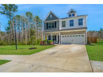 Charming two-story home with a well-manicured lawn and a two-car garage with a beautiful blue sky overhead at 204 Torslanda Ln, Summerville, SC 29486