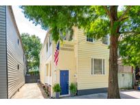 Charming yellow home featuring a blue door and an American flag, nestled under lush green trees at 21 America St, Charleston, SC 29403