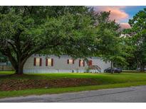 Charming single-story home featuring a well-manicured lawn and lush trees at 303 Crestwood Dr, Moncks Corner, SC 29461