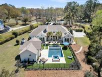 Expansive backyard featuring a pool, spa, outdoor seating, and lush landscaping at 7858 Gull Bay Dr, Awendaw, SC 29429