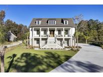 Elegant two-story home with a grand staircase, double balconies, and lush green lawn at 8638 Scottish Troon Ct, North Charleston, SC 29420