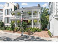 Charming two-story home featuring a double porch, brick pathway, and lush landscaping at 10 Water St, Charleston, SC 29401