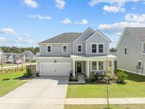 Charming two-story home features a well-manicured lawn, attached two-car garage, and welcoming front porch at 158 Woodland Oak Way, Summerville, SC 29485