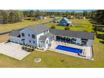 Stunning aerial view of a sprawling white farmhouse with a pool and lush green lawn at 161 Ryefield Ln, Ridgeville, SC 29472
