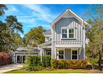 Charming two-story home featuring a gray exterior, well-manicured lawn, and lush landscaping with mature trees at 1810 Fleming Woods Rd, Charleston, SC 29412