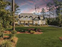 Stunning exterior showcasing a beautifully landscaped front yard and charming two-story home at sunset at 4086 Lady Banks Ln, Ravenel, SC 29470