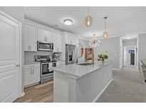 Bright kitchen with white cabinets, stainless steel appliances, and a large center island with quartz countertops at 500 Bucksley Ln # 308, Charleston, SC 29492