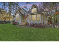 Charming exterior with lush lawn, blossoming flowers, and an American flag displayed at 5758 Chisolm Rd, Johns Island, SC 29455