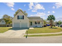 Charming home featuring a two-car garage, manicured lawn, and inviting front porch at 112 Retriever Ln, Goose Creek, SC 29445