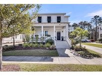 Charming two-story white home with a welcoming front porch and lush landscaping at 1391 Crane Creek Dr, Mount Pleasant, SC 29466