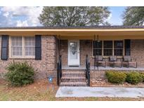 Charming brick home entrance featuring a covered front porch with seating and classic design elements at 1404 Ivy Isle Dr, Charleston, SC 29412