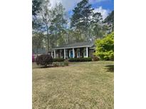 Inviting single-story home with a manicured lawn, mature trees, and a charming blue front door at 202 Woodland Dr, Summerville, SC 29485