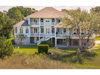 Beautiful elevated home with a porch and lush landscaping offers stunning curb appeal at 24 Waterway Island Dr, Isle of Palms, SC 29451