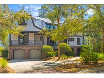 Charming two-story home featuring a brick façade, metal roof, second story porch, and manicured landscaping at 3121 Marshgate Dr, Johns Island, SC 29455
