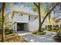 Charming home featuring a light gray exterior with covered parking and a lush, tree-filled yard at 32 Twin Oaks Ln, Isle of Palms, SC 29451