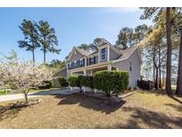 Charming two-story home with a well-manicured lawn, mature trees, and a welcoming front porch at 327 Freeland Way, Moncks Corner, SC 29461