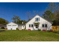 Charming home featuring white siding, a black roof, manicured lawn and a detached two car garage at 418 Geddes Ave, Charleston, SC 29407