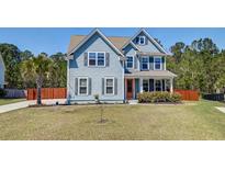 Charming two-story home with light blue siding, orange front door, manicured lawn, and mature landscaping at 5525 Alpine Dr, Summerville, SC 29483