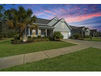 Charming single-story home featuring manicured lawn, palm trees, and a two-car garage at 566 Four Seasons Blvd, Summerville, SC 29486