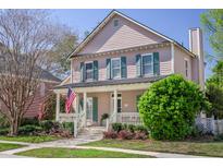 Charming two-story home with a welcoming front porch, complemented by lush landscaping and an American flag at 772 Preservation Pl, Mount Pleasant, SC 29464