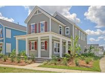 Charming two-story home featuring a welcoming front porch, gray siding, and vibrant red shutters at 820 Gentle Breeze Dr, Summerville, SC 29486