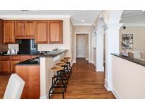 Bright kitchen features dark countertops, wood cabinets, bar seating, and hardwood floors flowing through to the hallway at 1124 Clearspring Dr, Charleston, SC 29412