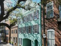 Charming teal townhome with black shutters and a covered entrance, nestled among historic brick buildings at 12 Elliott St # A, Charleston, SC 29401