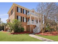 Charming red brick home with a double front porch, black shutters, and manicured landscaping at 1369 Tidal Creek Cv, Charleston, SC 29412