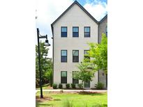 A striking three-story home featuring a painted brick facade, complemented by black framed windows and professional landscaping at 1510 Cecile St, Mount Pleasant, SC 29464