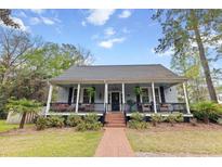 Charming single-story home with inviting front porch, brick walkway, and lush landscaping at 321 S Laurel St, Summerville, SC 29483