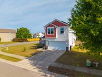 Two-story home with an attached garage, neutral siding, and a red trimmed gable under a bright blue sky at 4818 Pitkin Ave, Ladson, SC 29456