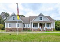Charming two-story home with a stone facade, flag pole and a welcoming front porch at 4846 Causey Pond Rd, Awendaw, SC 29429