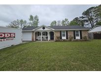 Charming brick home with a manicured lawn, a front porch, and black shutters at 4984 Foxwood Dr, North Charleston, SC 29418