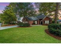 Charming brick home featuring a well-manicured lawn, mature trees, and an inviting entrance at 102 Kapalua Run, Summerville, SC 29483