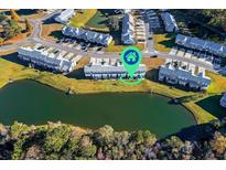 An aerial view of townhomes near a pond, providing serene waterfront living and a scenic neighborhood ambiance at 128 Black River Dr, Summerville, SC 29485