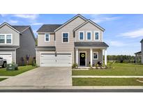 Charming two-story home featuring a spacious front lawn, attached garage, and welcoming entryway with decorative wreath at 157 Tuscan Sun St, Summerville, SC 29485