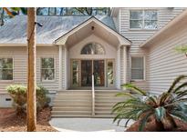 Welcoming front entrance with an arched window, wooden stairs, and lush landscaping at 3180 Pine Needle Ln, Seabrook Island, SC 29455