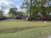 Charming one-story brick home with a spacious front yard and blooming azaleas at 1121 Inverness Ln, Hanahan, SC 29410