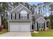 Charming two-story home boasts a well-manicured lawn, attached two-car garage, and classic architectural details at 1158 Peninsula Cove Dr, Charleston, SC 29492