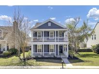 Charming two-story home with a welcoming front porch and beautifully landscaped front yard on a sunny day at 117 Red Leaf Blvd, Moncks Corner, SC 29461