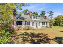 Charming two-story home with white siding, black shutters, mature trees, and landscaped front yard at 1300 S Main St, Summerville, SC 29483