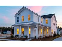 Charming two-story white home with a covered porch and beautiful architectural details at sunset at 1435 Clay Field Trl, Summerville, SC 29485