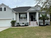 Charming home with a landscaped yard and a welcoming front porch with beautiful flowers at 1433 Oakhurst Dr, Mount Pleasant, SC 29466